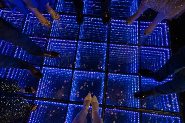 Overhead view of an infinity mirror LED dance floor glowing blue and purple at a birthday party