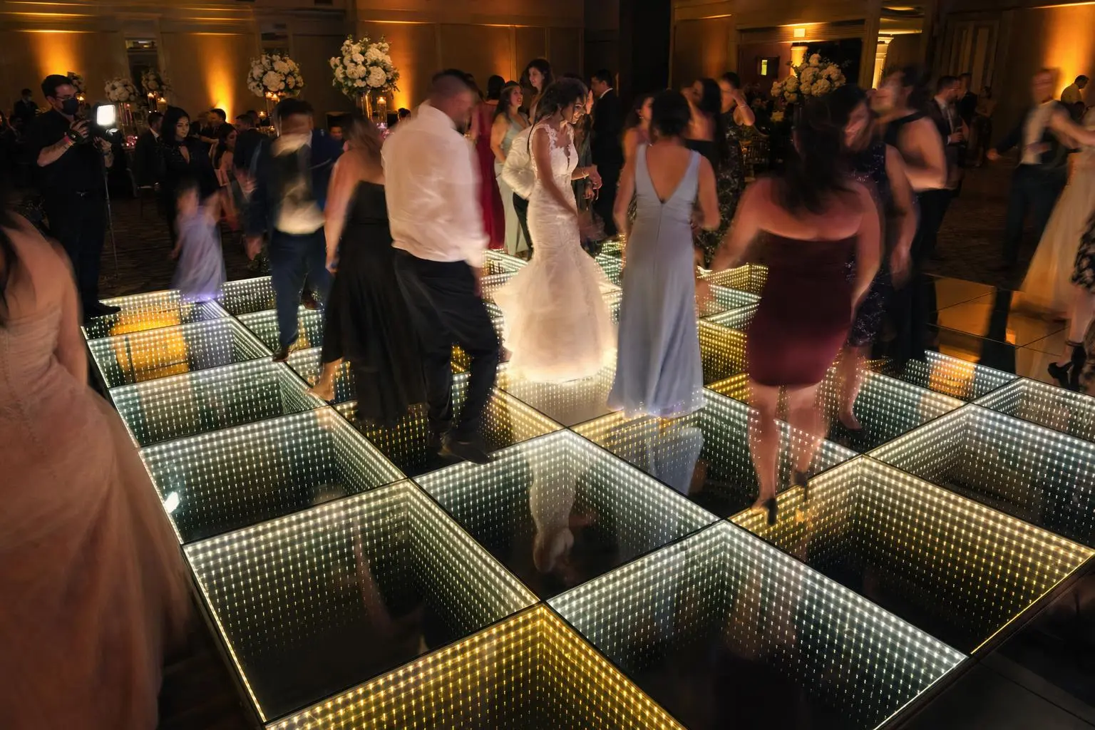 Guests dancing on a 16 x 16 ft infinity mirror LED dance floor at a wedding reception