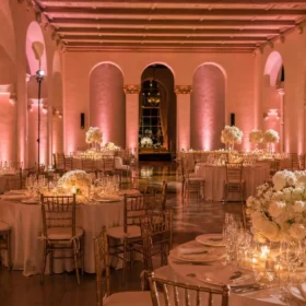 Wedding reception lit with blush pink wireless LED uplights and pin spots on centerpieces