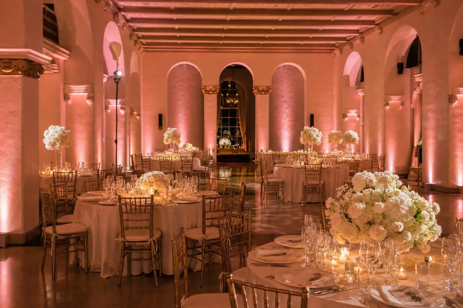 Wedding reception lit with blush pink wireless LED uplights and pin spots on centerpieces