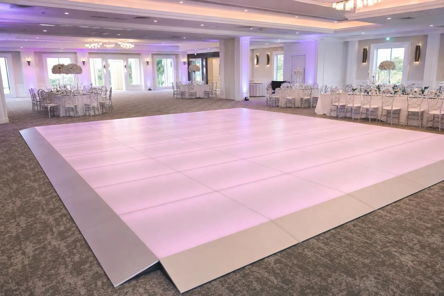 White matte LED dance floor lit in pink and lavender before a reception